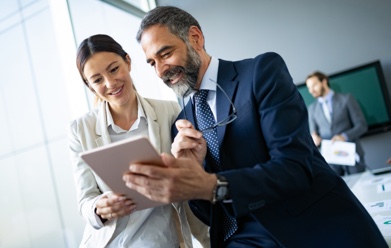A man and woman holding a tablet device together.