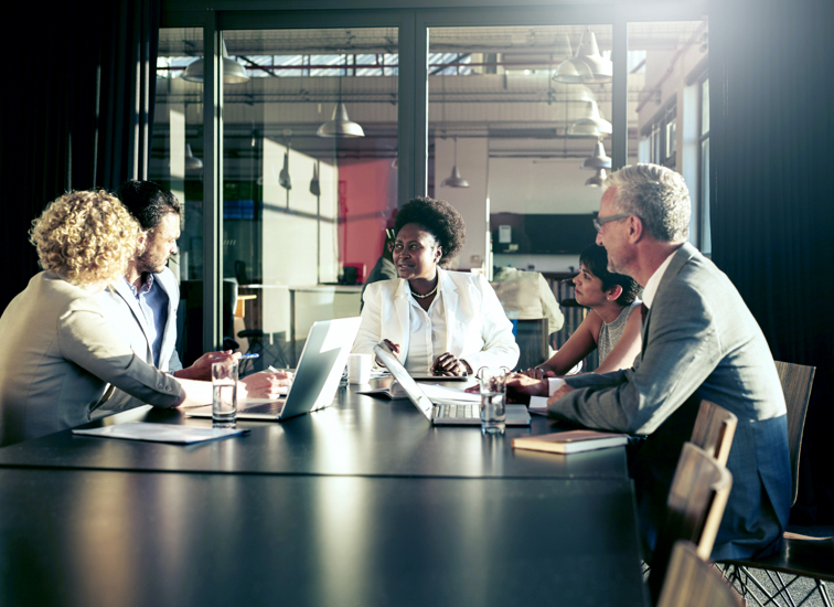 Five business associates seated around a table in a conference room