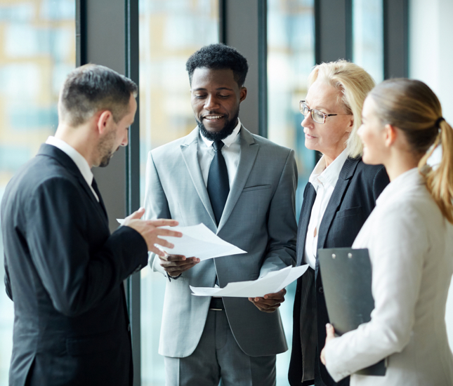 Two men and women standing together having a discussion.
