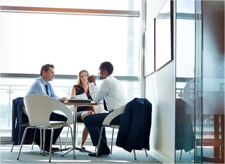 Two men and a woman seated around a table having a discussion.