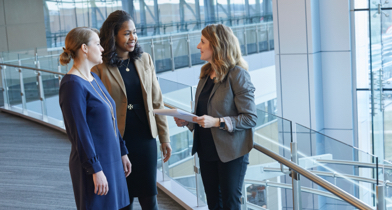 Three women standing inside a glass office building