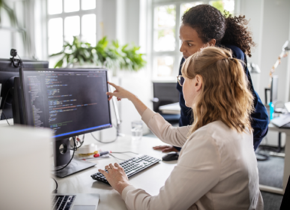Two associates at a workstation looking at a computer monitor.
