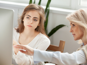 Two women looking at a computer monitor.