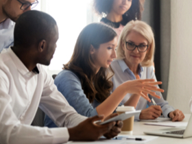 A small group of associates standing and seated at a conference table.