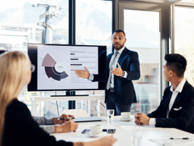 A businessman giving a presentation to other associates seated at a table.