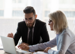 A business man and business woman looking at a laptop monitor.