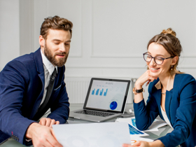 A man and a woman seated at a desk looking a financial papers.