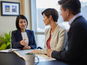 A woman and another couple seated at a table reviewing financial papers.