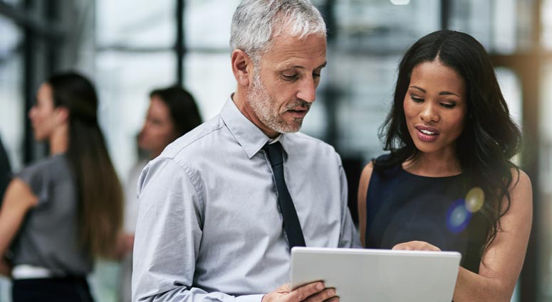 A man and woman looking at a tablet device.